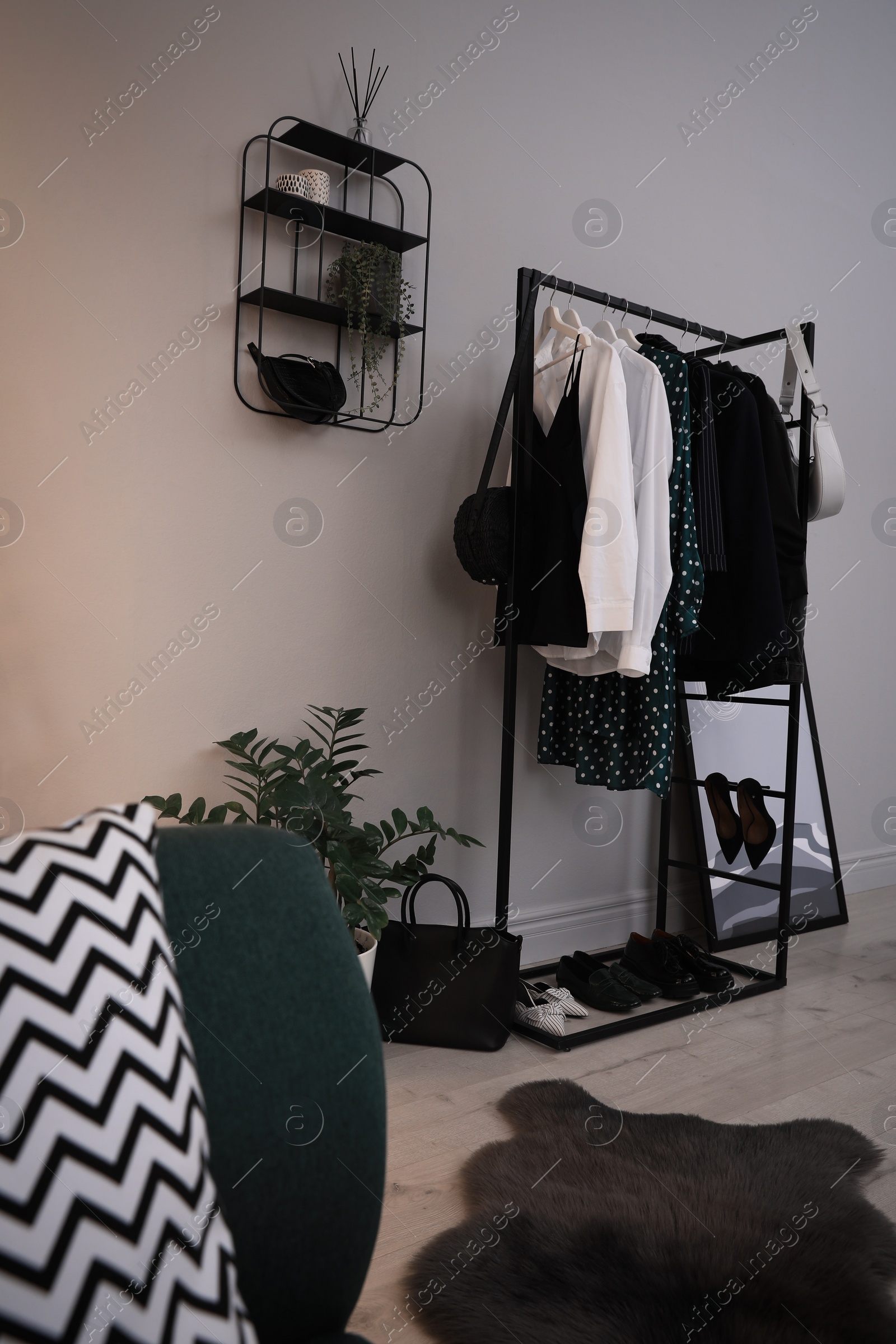 Photo of Rack with stylish women's clothes and shoes in dressing room