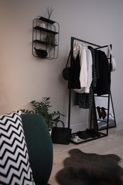 Rack with stylish women's clothes and shoes in dressing room