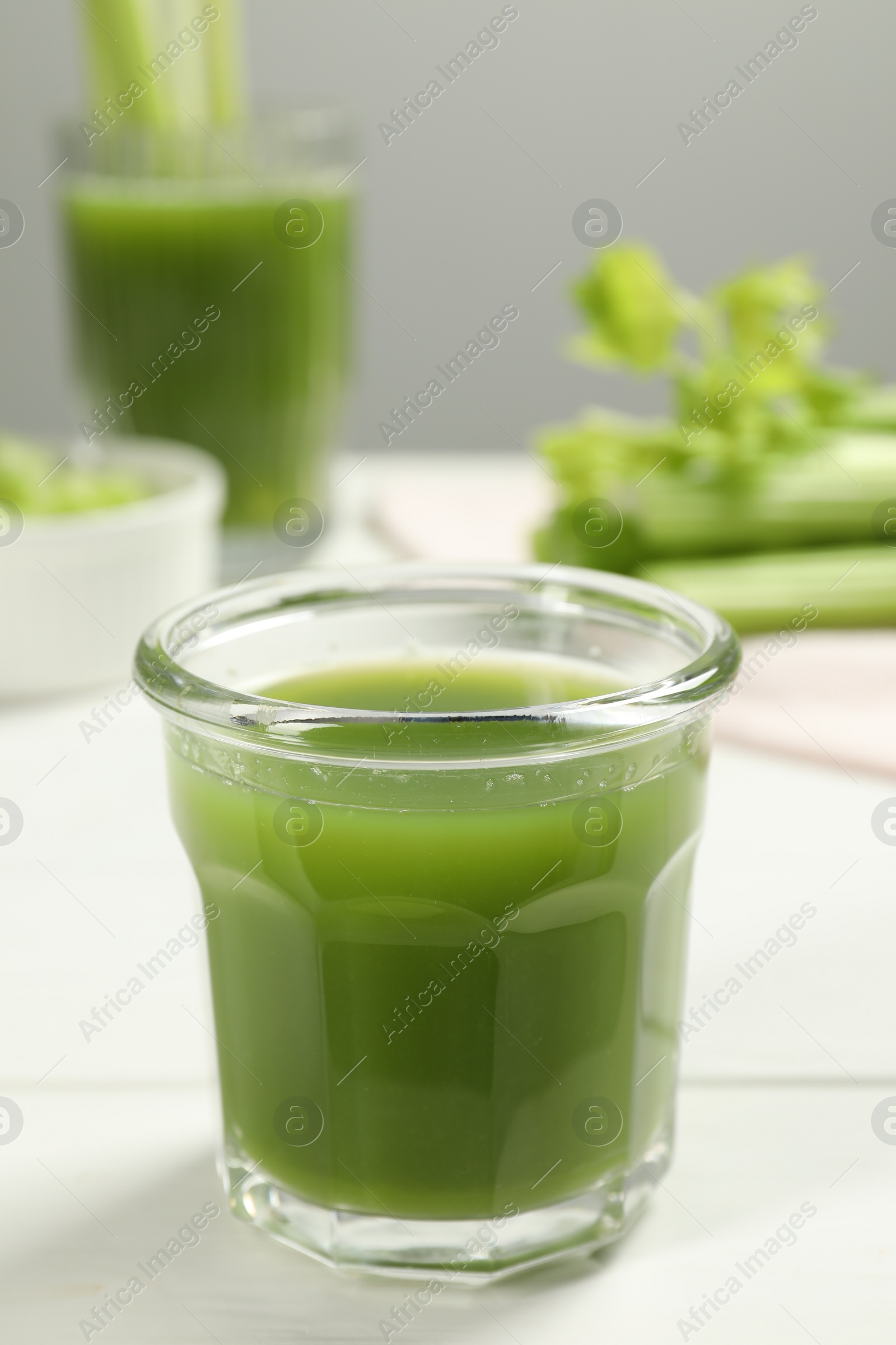 Photo of Glass of fresh celery juice on white table, closeup