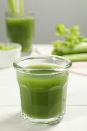 Photo of Glass of fresh celery juice on white table, closeup