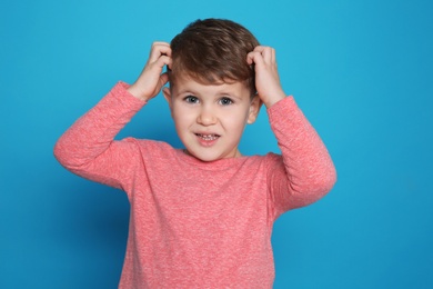 Photo of Little boy scratching head on color background. Annoying itch