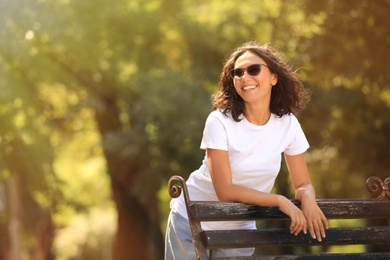 Photo of Beautiful young woman standing near bench in park