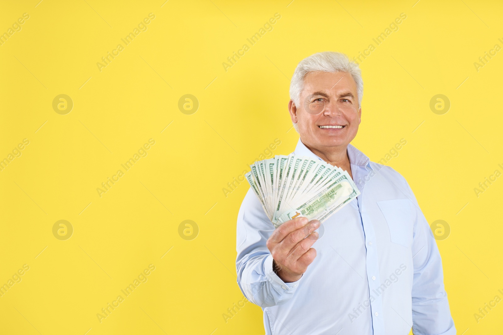 Photo of Happy senior man with cash money on yellow background. Space for text