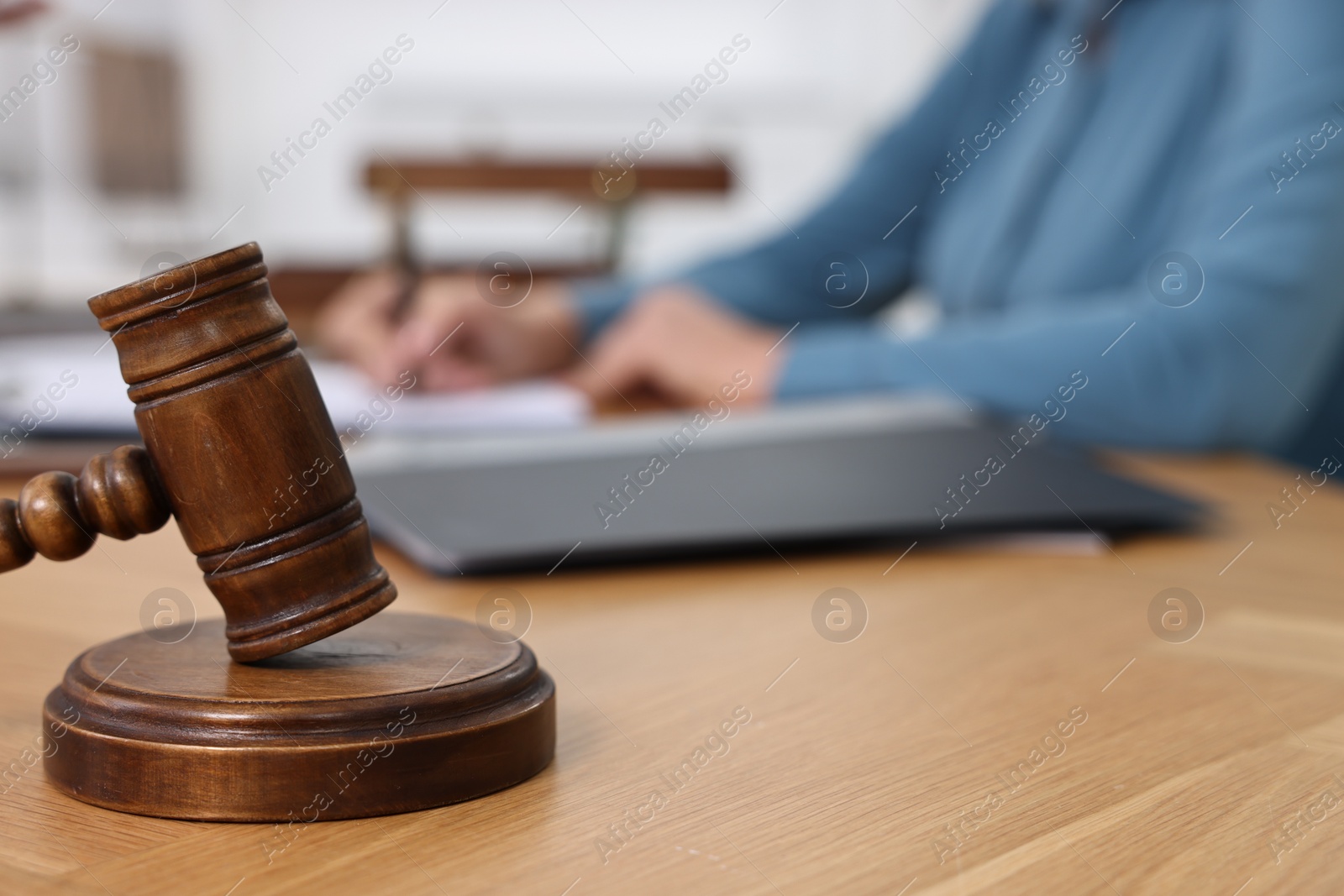 Photo of Senior woman signing document in lawyer's office, focus on gavel