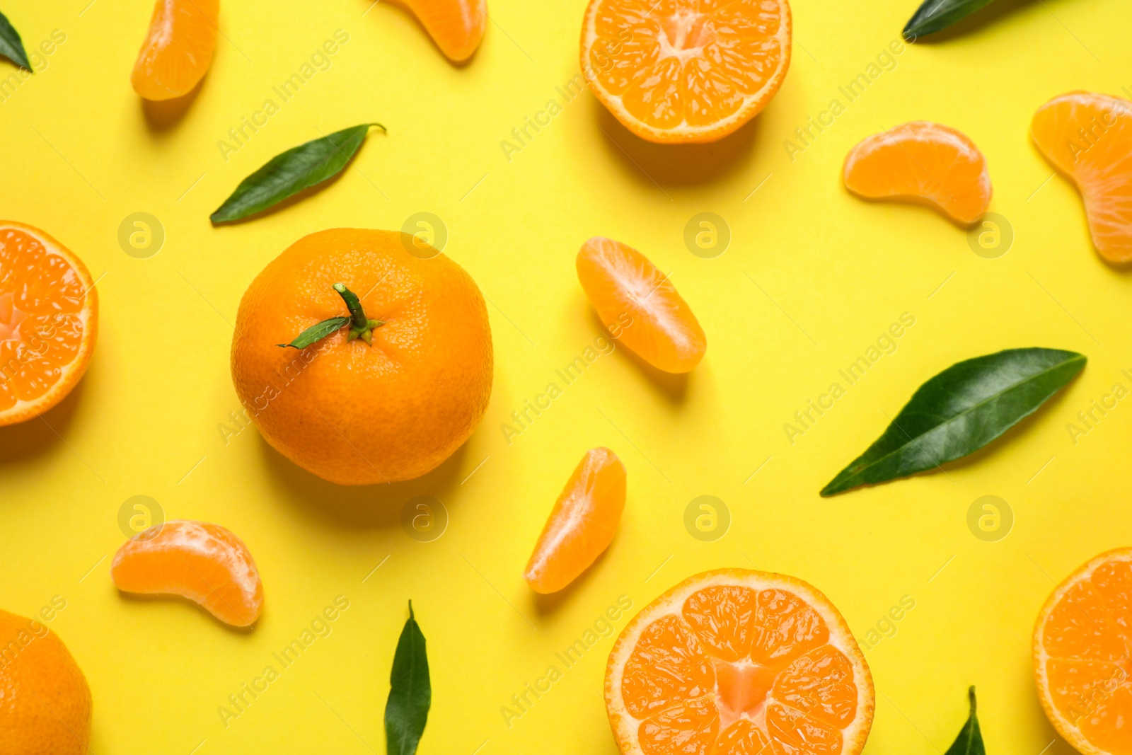 Photo of Flat lay composition with fresh ripe tangerines and leaves on yellow background. Citrus fruit