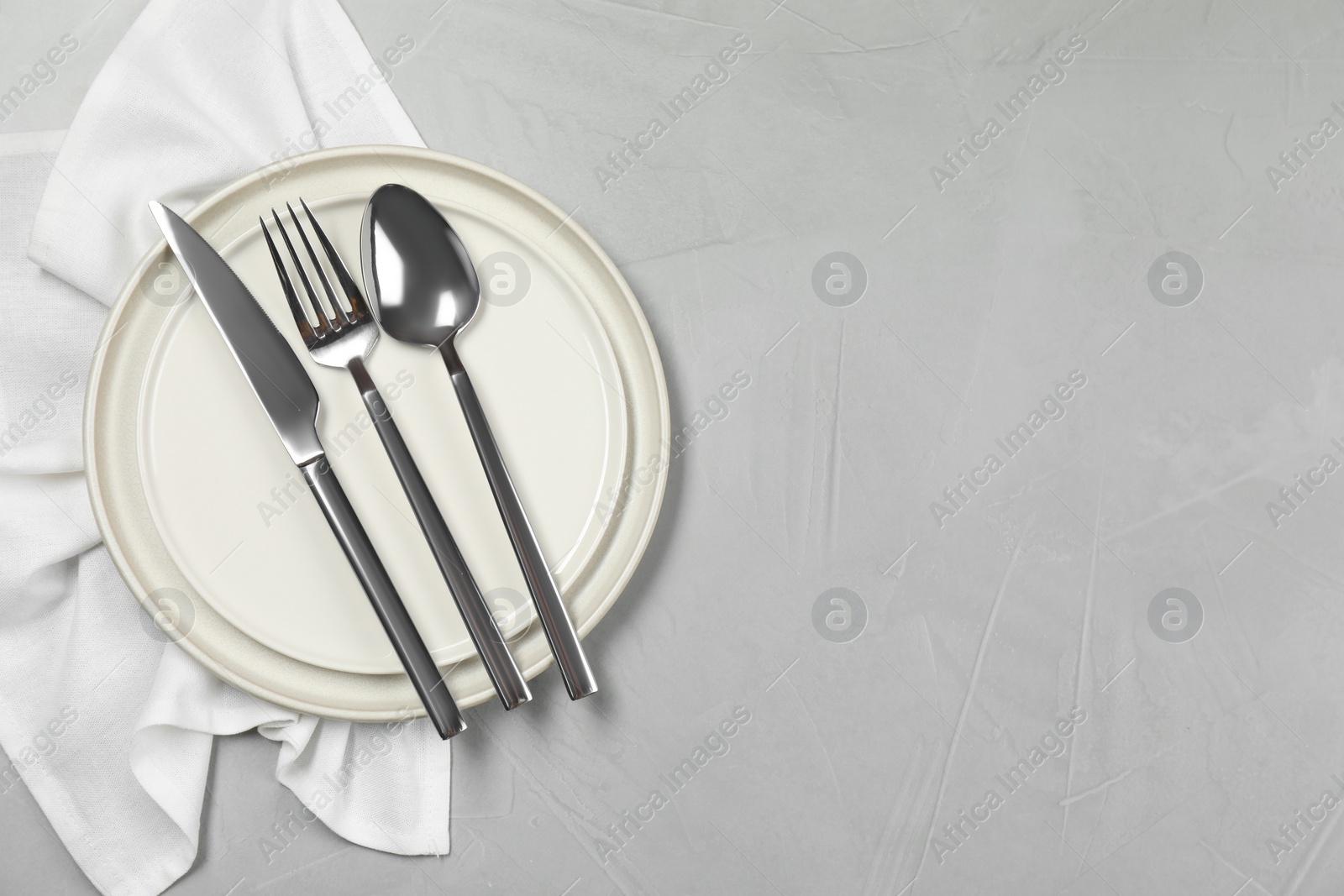 Photo of Stylish setting with elegant cutlery on grey table, top view. Space for text