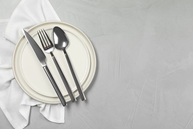 Stylish setting with elegant cutlery on grey table, top view. Space for text