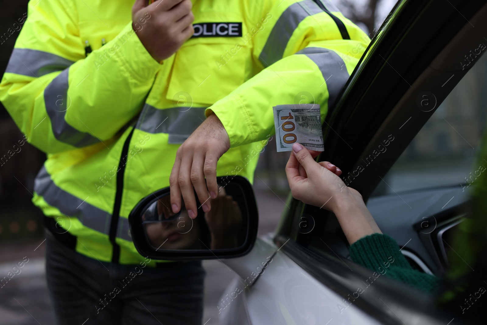 Photo of Woman giving bribe to police officer out of car window, closeup