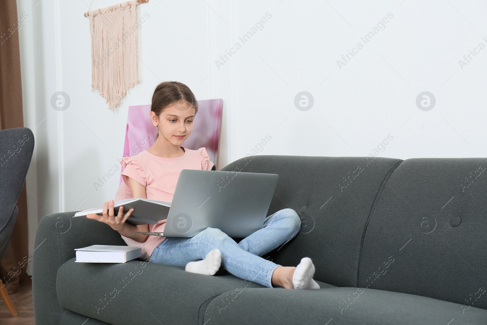 Photo of Girl with laptop and books on sofa at home