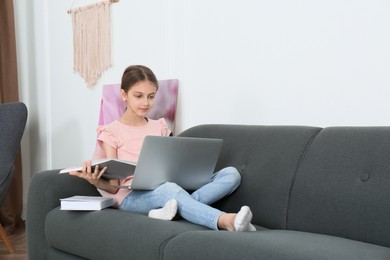 Photo of Girl with laptop and books on sofa at home
