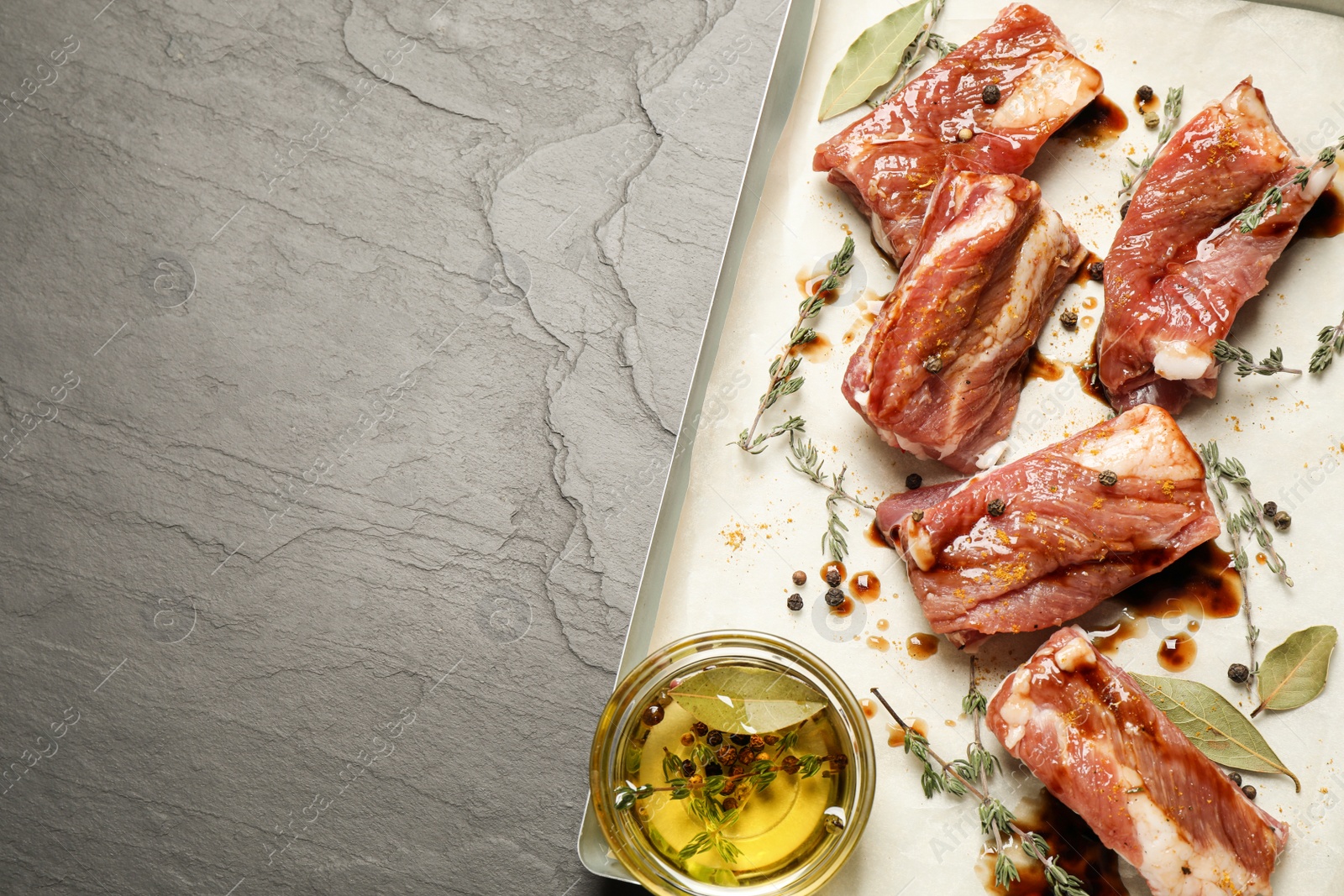 Photo of Raw marinated ribs on black table, top view. Space for text