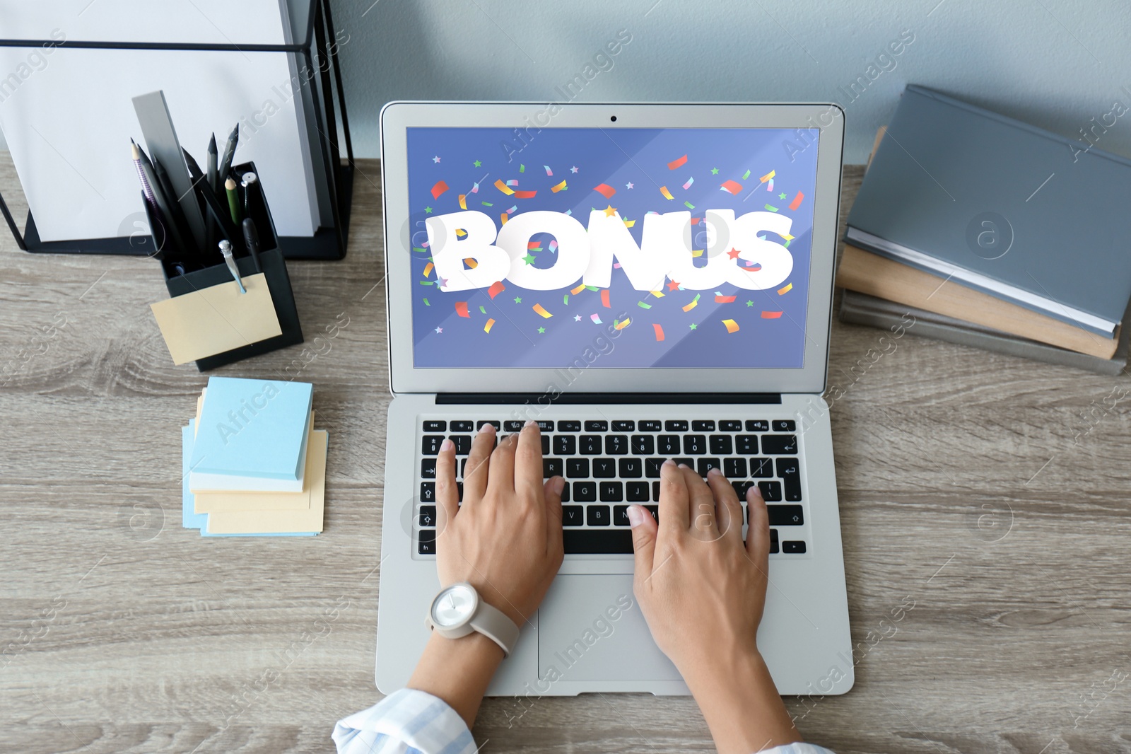 Image of Bonus gaining. Woman using laptop at wooden table, above view. Illustration of falling confetti and word on device screen