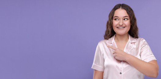 Image of Smiling woman with braces pointing at something on violet background. Banner design with space for text