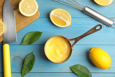 Delicious lemon curd and fresh fruits on light blue wooden table, flat lay