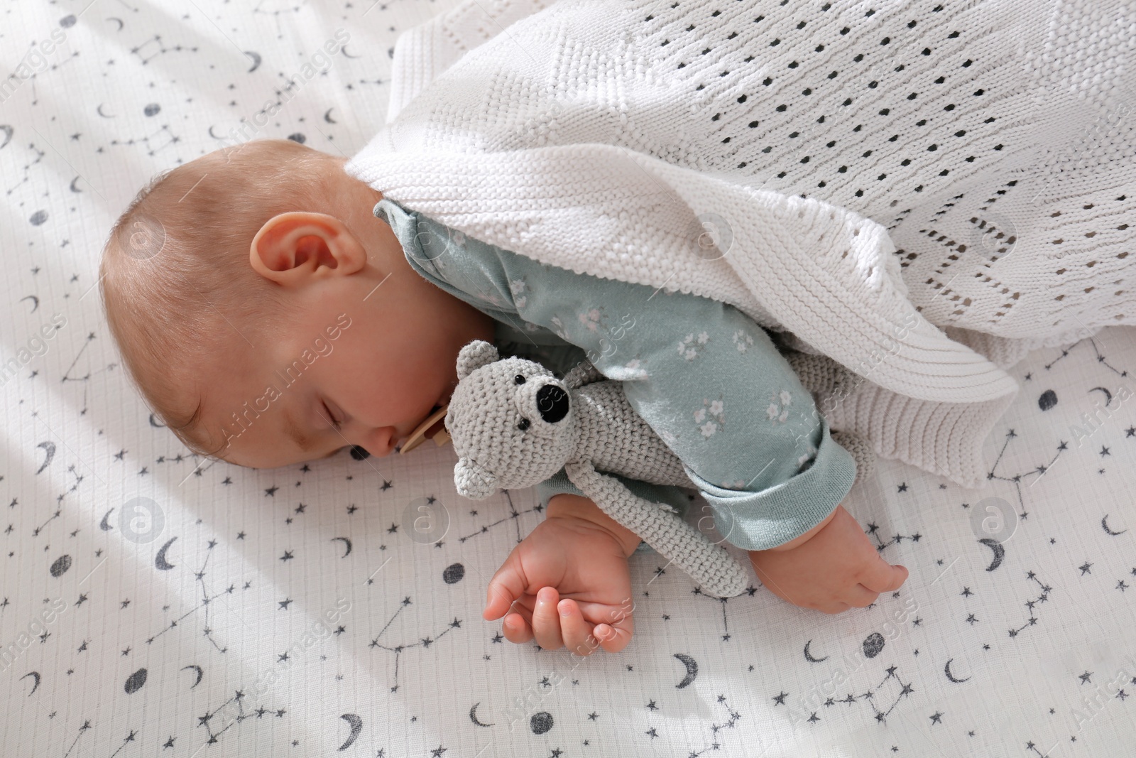 Photo of Adorable baby with toy sleeping in bed, above view