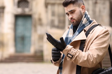 Photo of Handsome man in warm scarf on city street. Space for text