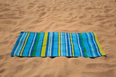 Photo of Soft bright striped beach towel on sand