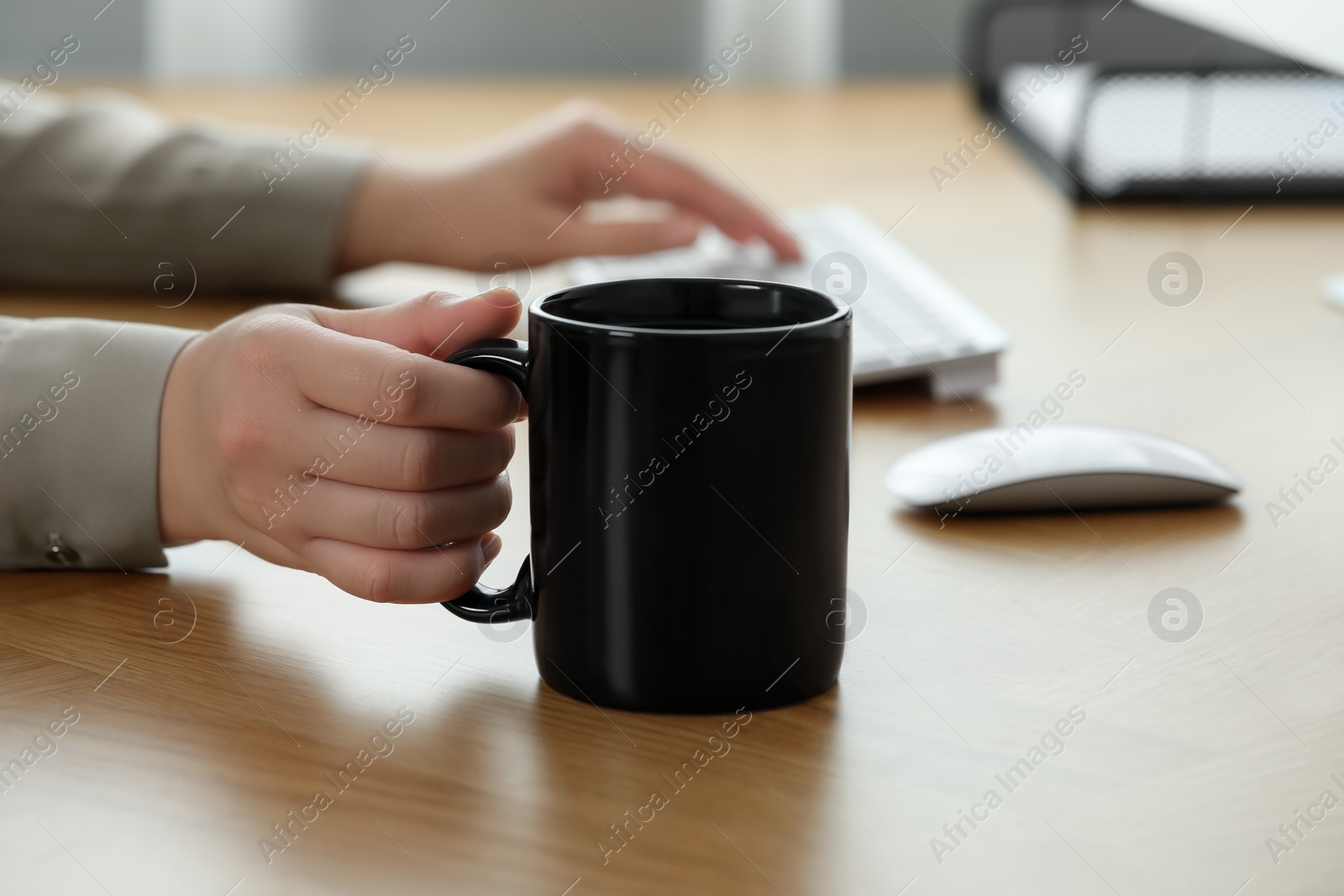 Photo of Woman with black ceramic mug at workplace, closeup