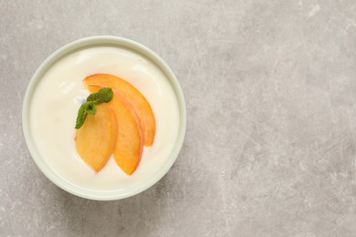 Photo of Delicious yogurt with fresh peach and mint on grey table, top view. Space for text