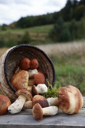 Photo of Fresh wild mushrooms on wooden table outdoors