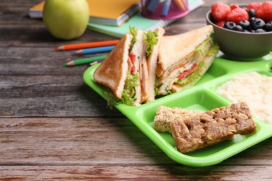 Photo of Serving tray of healthy food, stationery and space for text on wooden table. School lunch