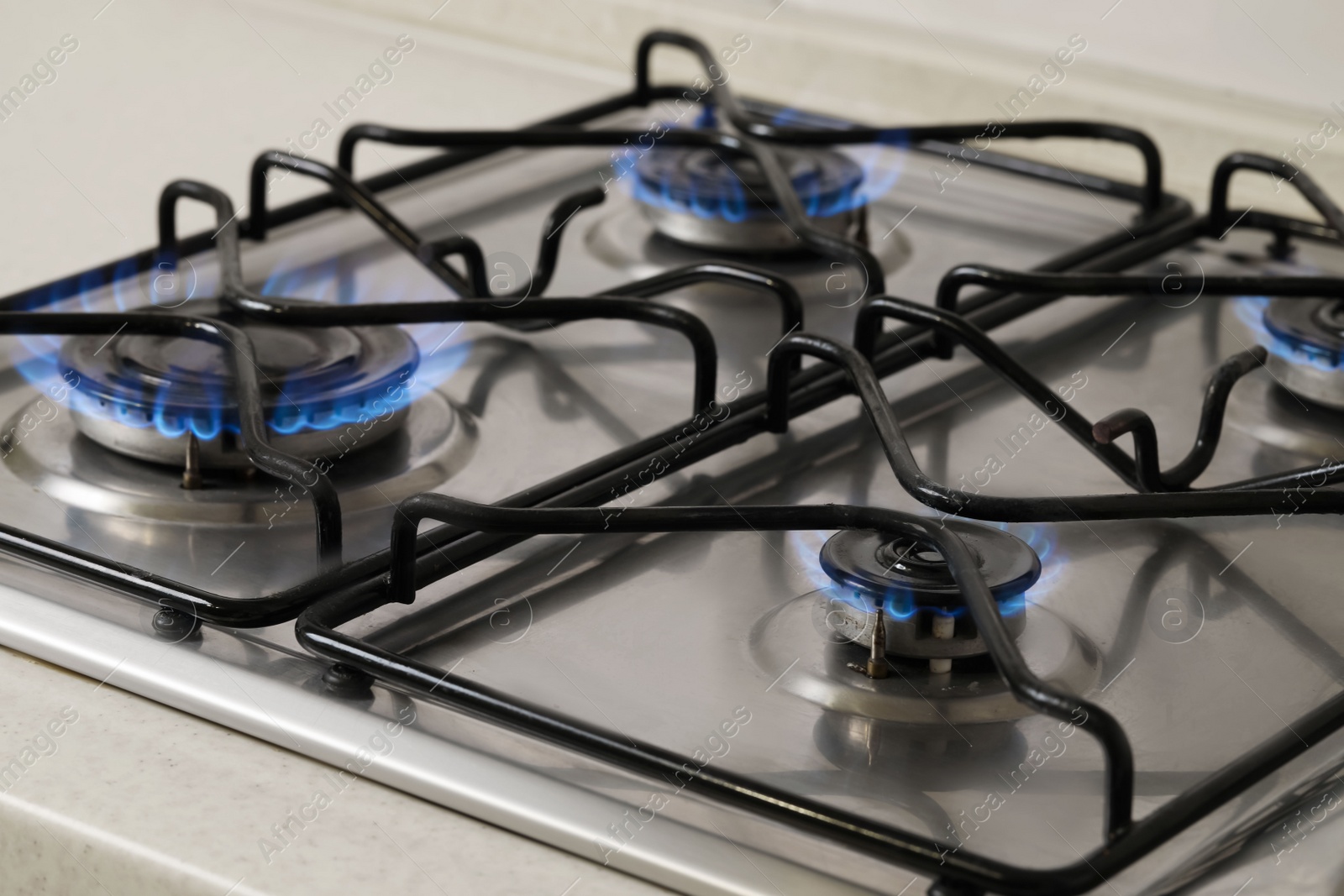 Photo of Gas cooktop with burning blue flames, closeup