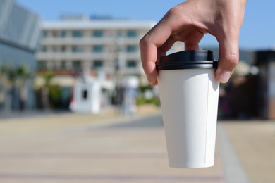 Photo of Woman holding takeaway coffee cup outdoors, closeup. Space for text