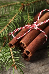 Cinnamon sticks and fir branches on wooden table, closeup