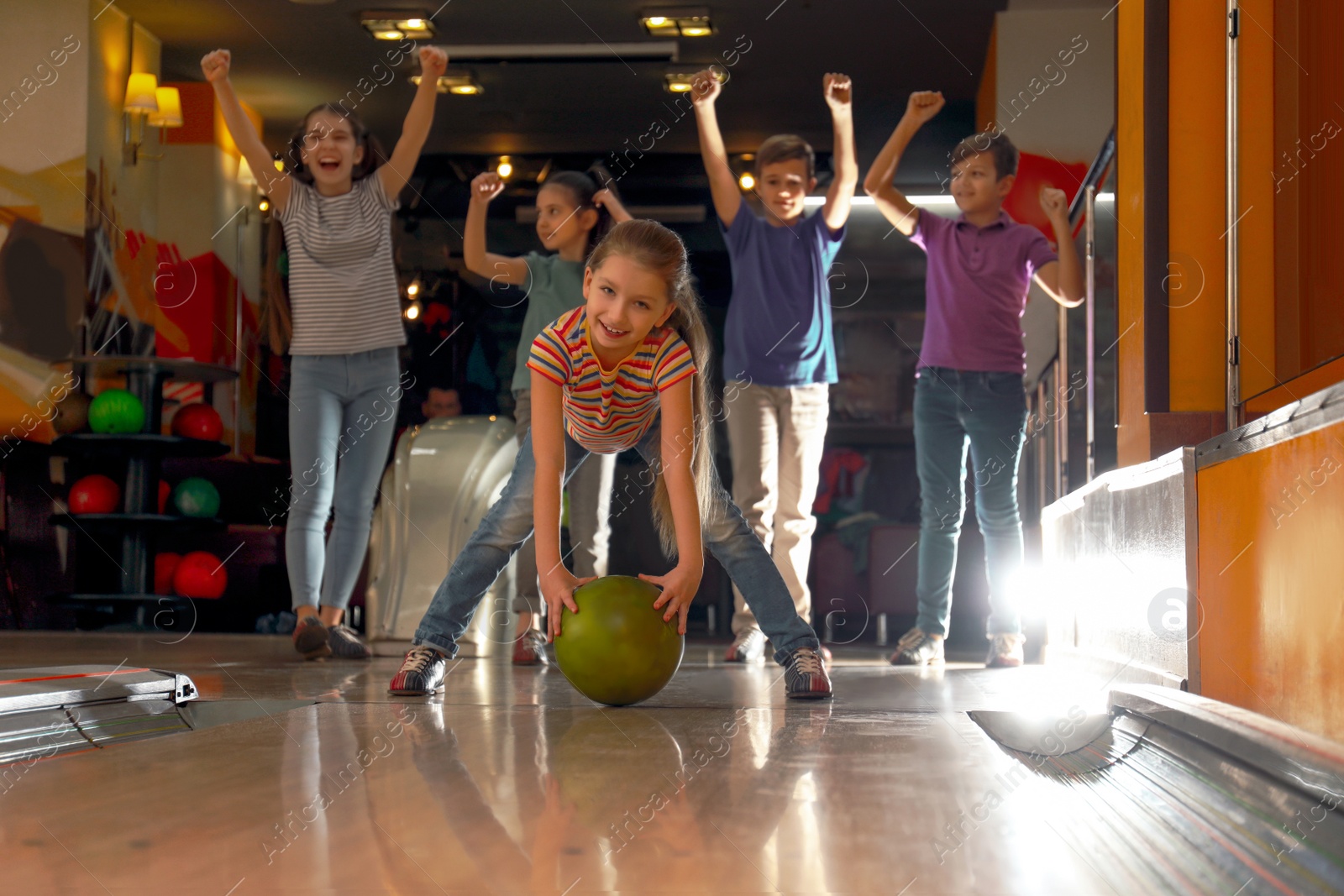 Photo of Girl throwing ball and spending time with friends in bowling club