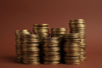 Photo of Many golden coins stacked on brown background