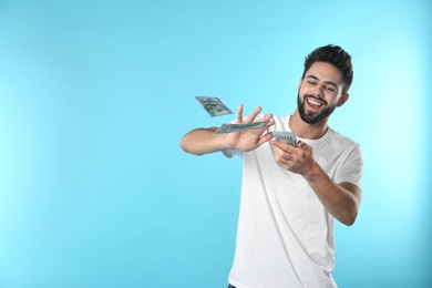 Photo of Happy young man throwing money on color background. Space for text