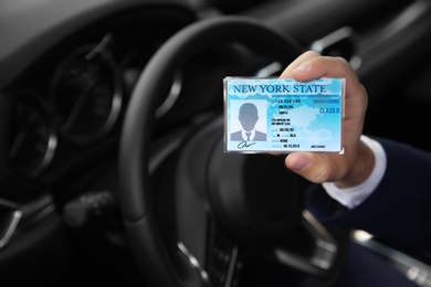 Photo of Man holding driving license in car, closeup. Space for text