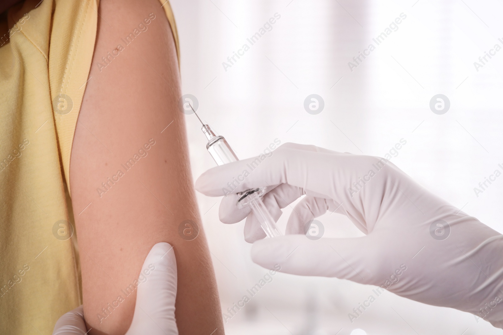 Photo of Doctor vaccinating young woman against Covid-19 in clinic, closeup