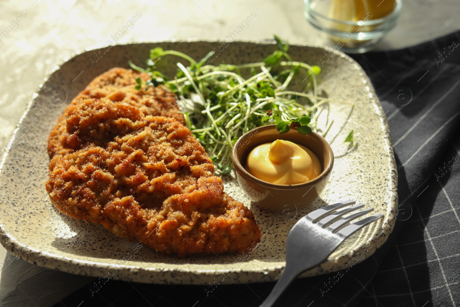 Photo of Tasty schnitzels served with sauce and microgreens on grey textured table, closeup