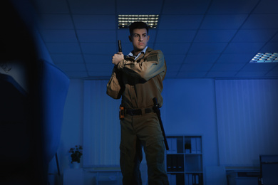 Photo of Professional security guard with handgun in dark office