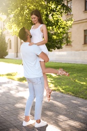 Lovely young couple dancing together in park on sunny day