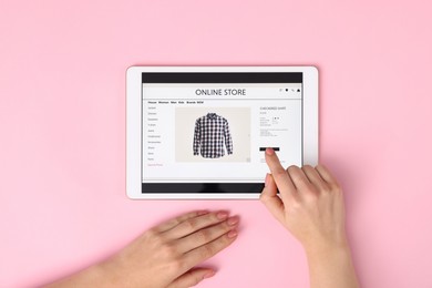 Photo of Woman with tablet shopping online on pink background, top view