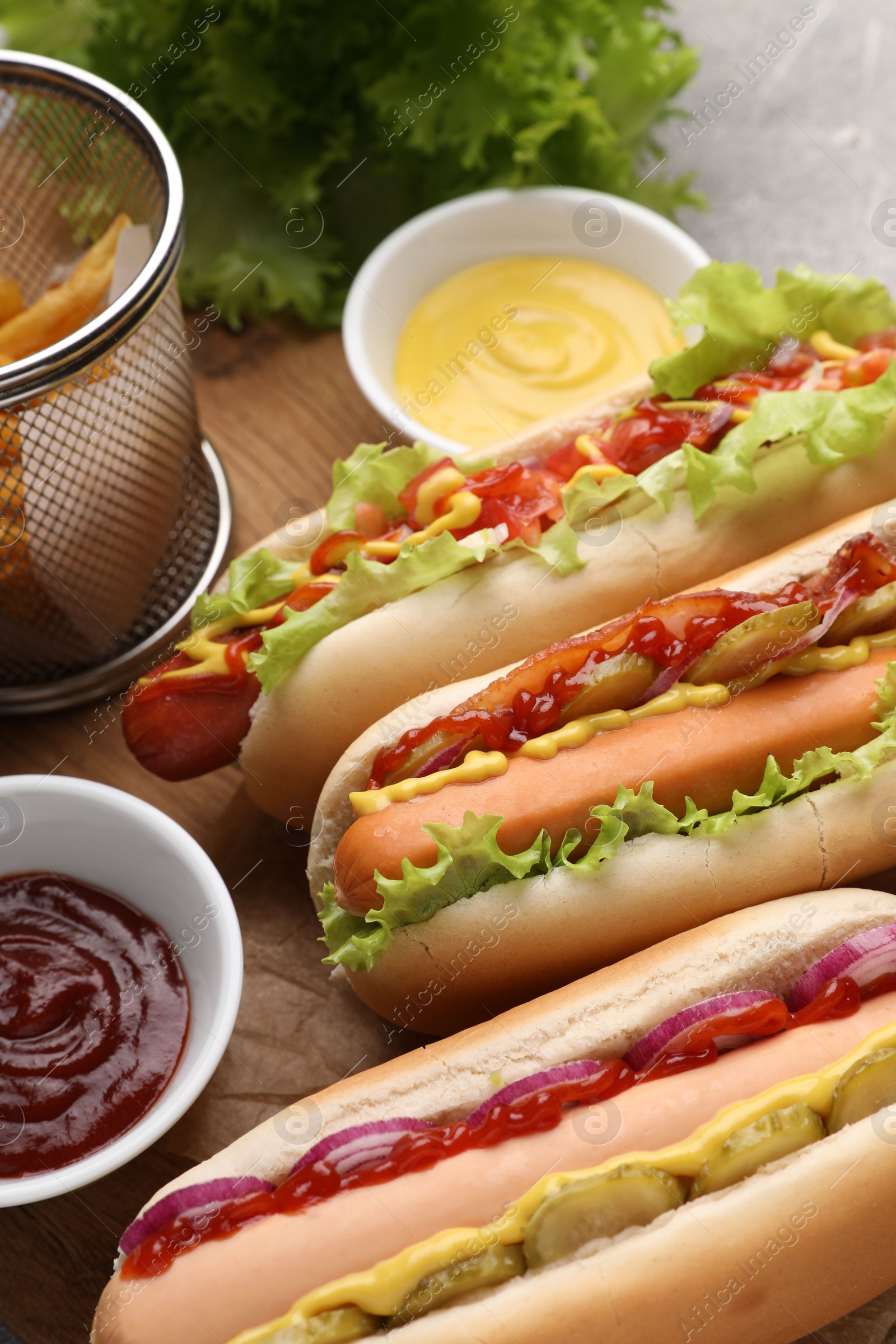 Photo of Delicious hot dogs with different toppings served on table, closeup