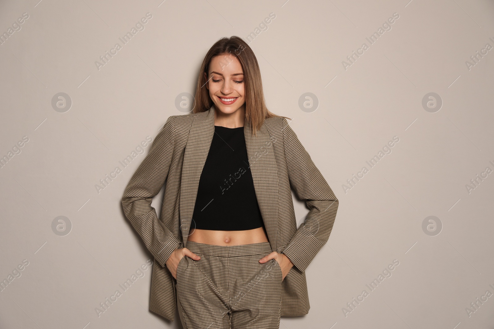 Photo of Portrait of beautiful young woman in fashionable suit on grey background. Business attire