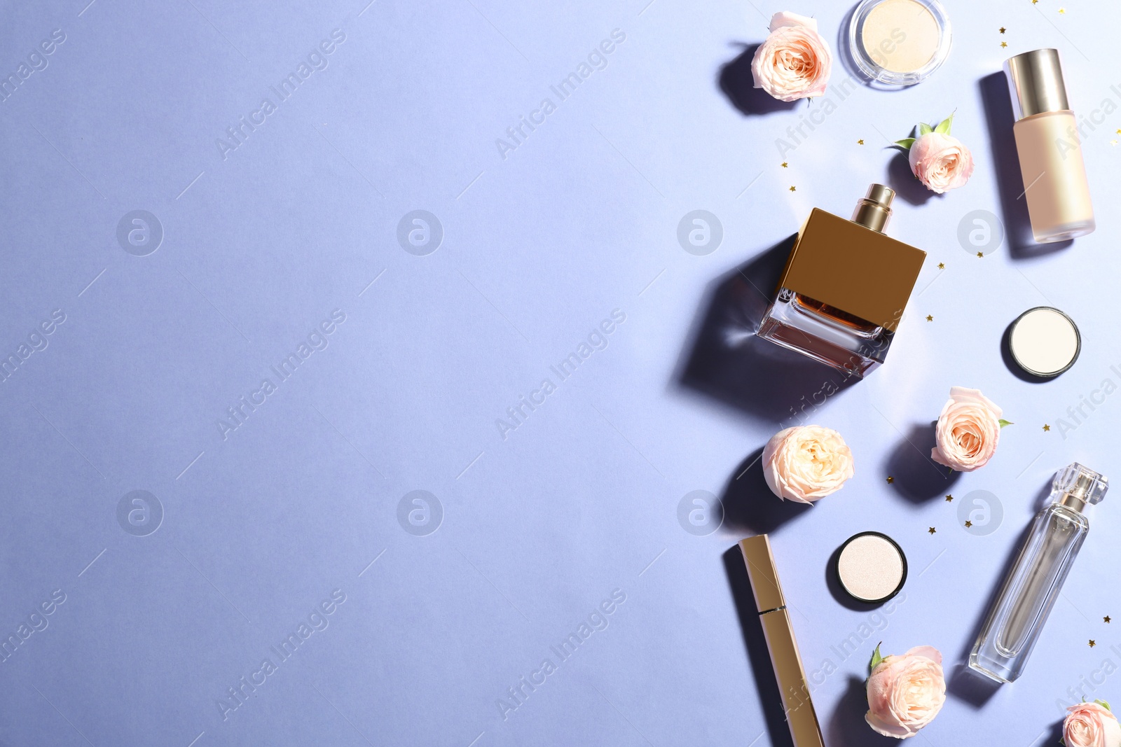 Photo of Flat lay composition with bottles of perfume, cosmetics and roses on color background. Space for text