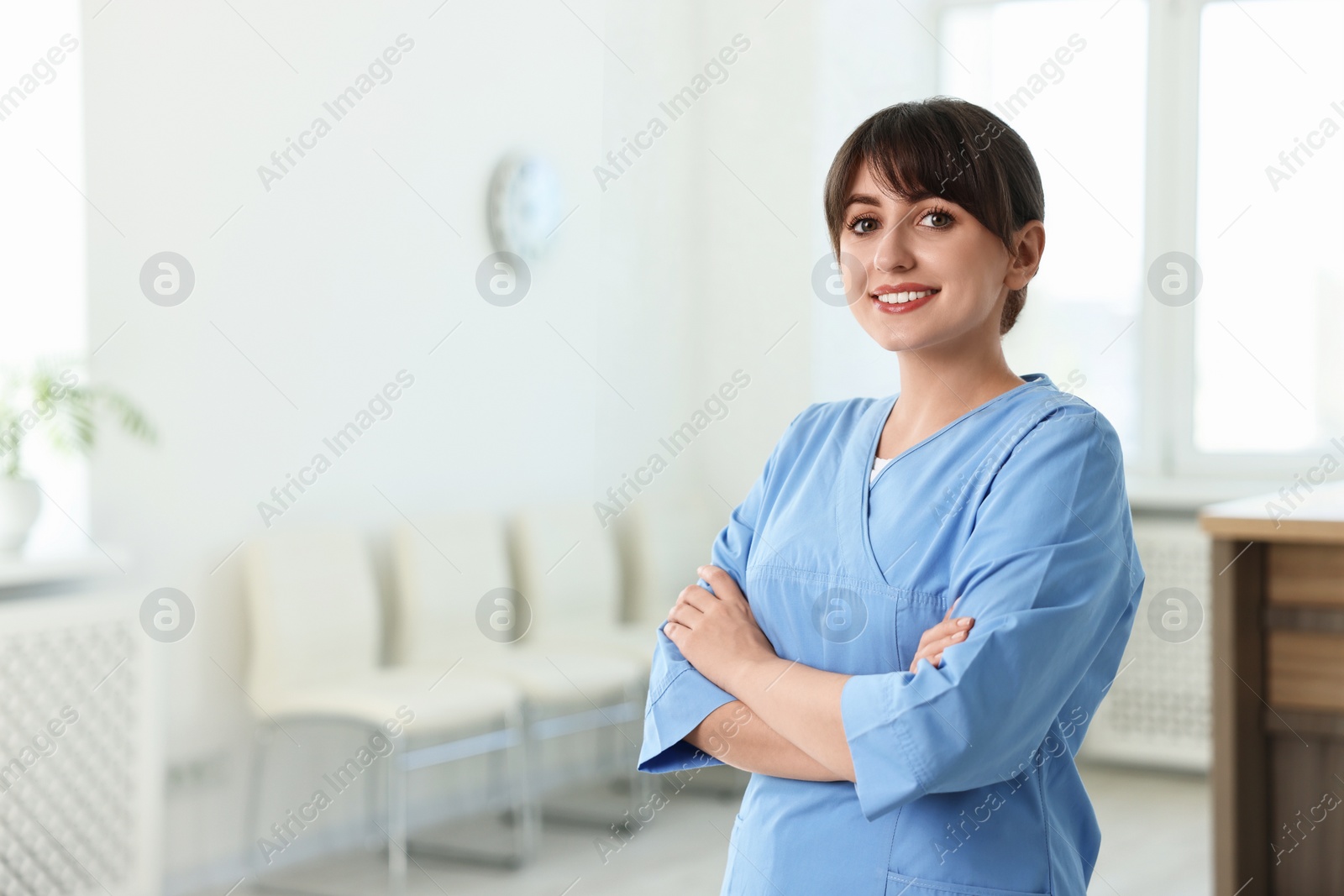 Photo of Portrait of smiling medical assistant with crossed arms in hospital. Space for text