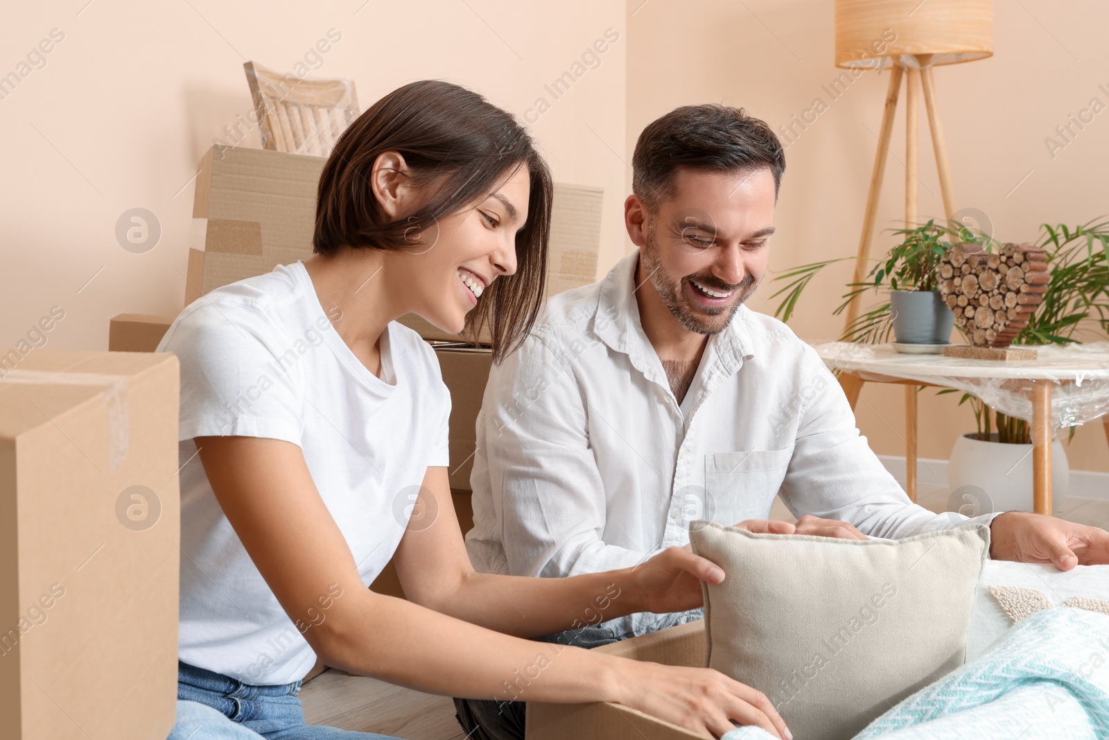 Photo of Happy couple unpacking box in new apartment. Moving day