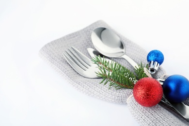 Photo of Cutlery, napkin and Christmas decor on white background, closeup. Festive table setting