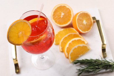 Photo of Glass of tasty Aperol spritz cocktail with orange slices and rosemary on white table, above view