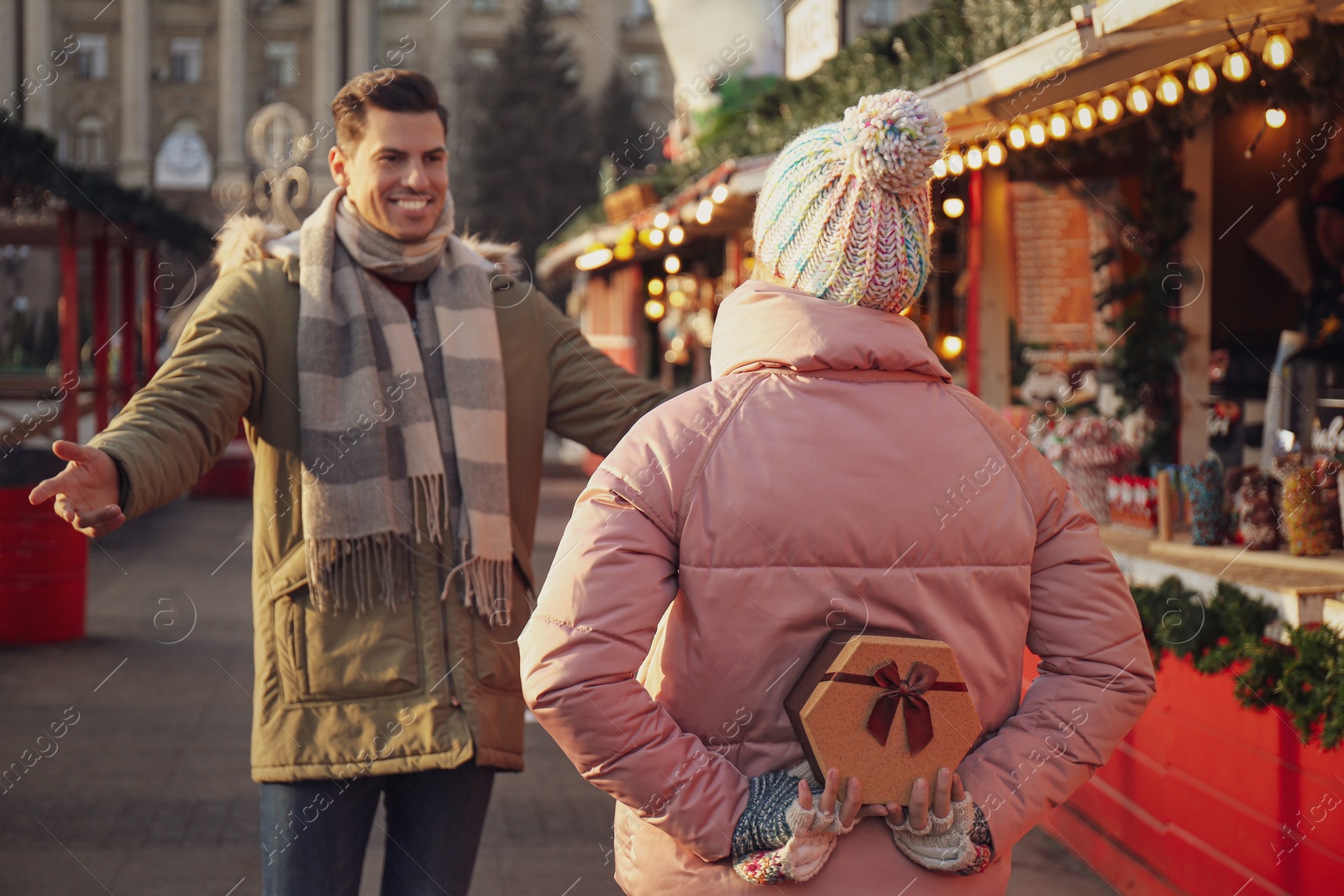 Photo of Young woman presenting Christmas gift to her boyfriend at winter fair