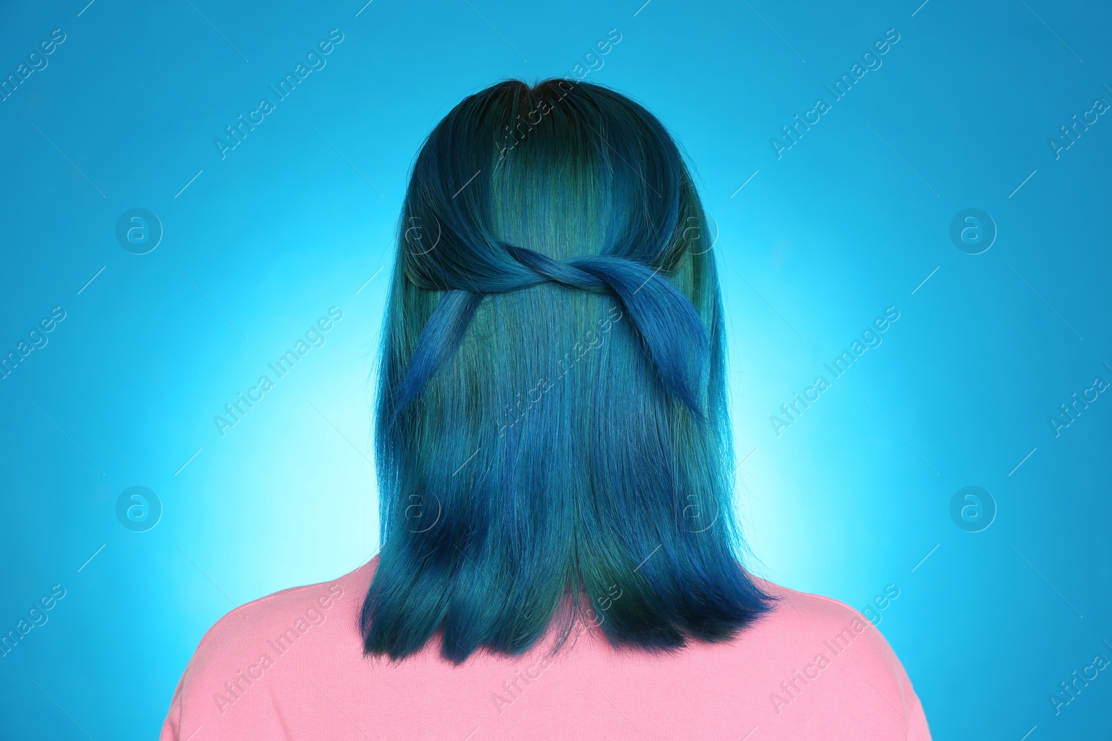 Photo of Woman with bright dyed hair on light blue background, back view