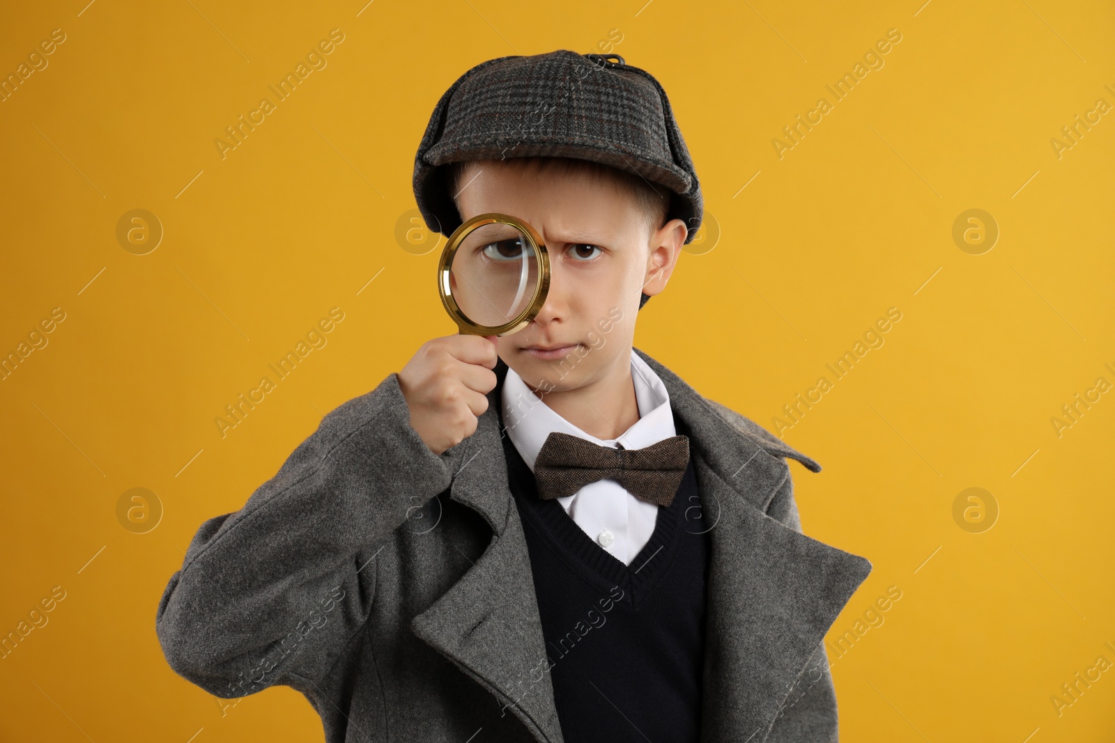 Photo of Cute little detective with magnifying glass on yellow background