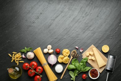 Photo of Different types of pasta, spices, garter and products on dark textured table, flat lay. Space for text