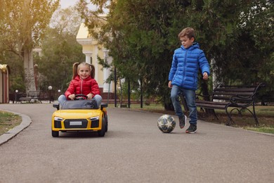 Cute little children with toy car and soccer ball having fun outdoors