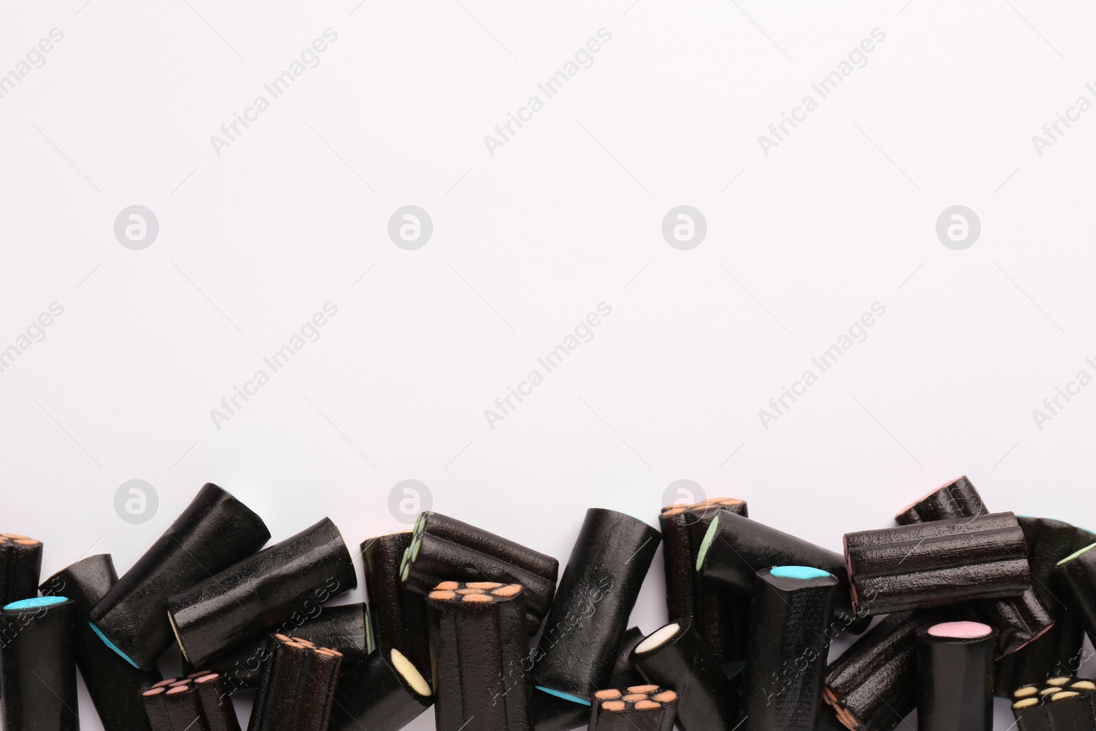 Photo of Tasty liquorice candies on light background, top view. Space for text